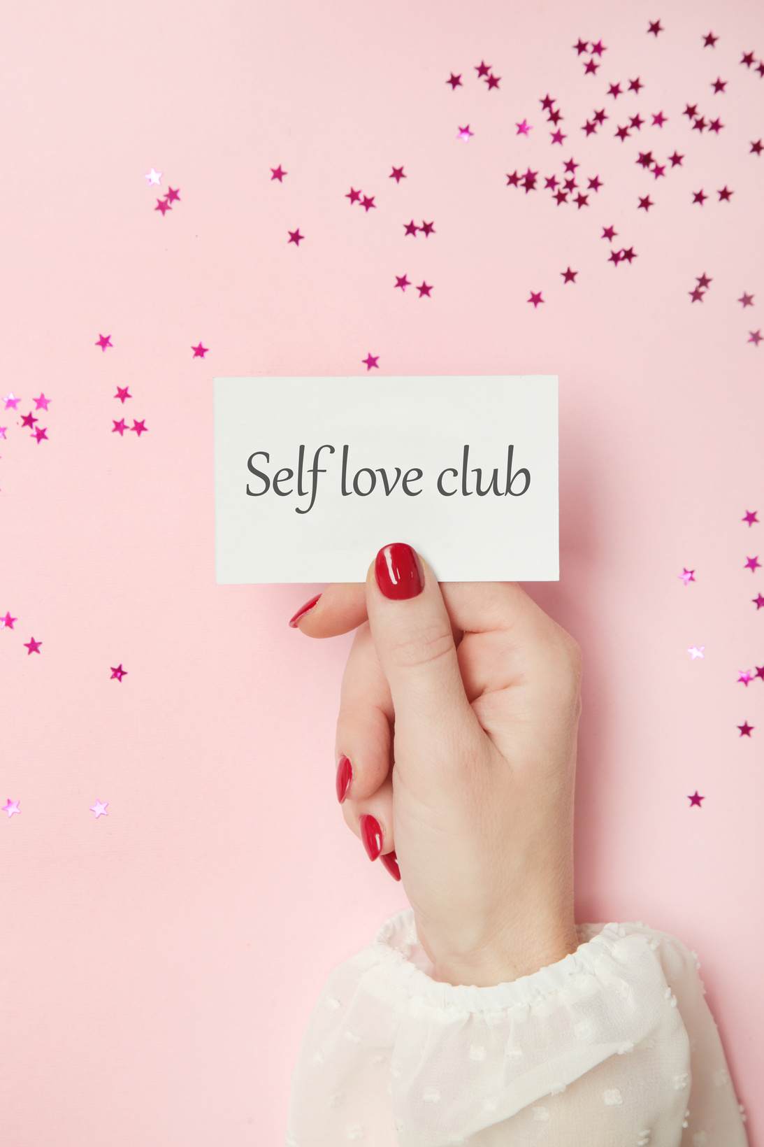 Woman holding card with Self Love Club motivational quote.